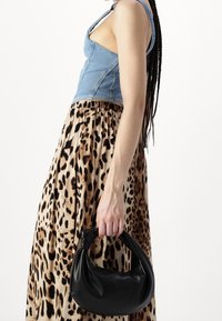 Denim crop-top, eläinkuosilla varustettu maxi-hame ja musta tekonahkainen käsilaukku, jossa on solmittu kahva. Keskity tekstuuriin ja kontrastisiin kuoseihin.