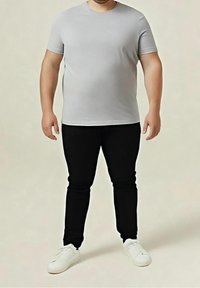 Camiseta gris de manga corta combinada con vaqueros negros de corte slim y zapatillas blancas. La tela parece suave, con un diseño ajustado y líneas limpias.