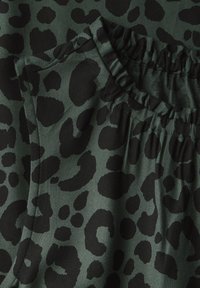 Tkanina w panterkę w ciemnozielonym kolorze z czarnymi plamami. Posiada elastyczny pas i chropowatą powierzchnię, podkreślającą wyraźne detale wzoru.