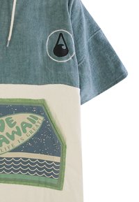 Poncho asciugamano con cappuccio in teal e crema, caratterizzato da una grafica a onda. Tessuto morbido e testurizzato con stampa del logo sul petto e nell'area tasca.