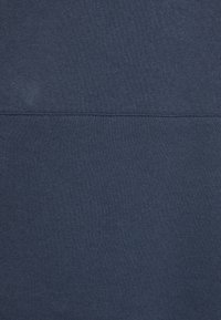 Mörkblå sweatshirttyg med en slät textur, med en horisontell sömdetalj över mitten.