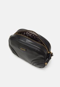 Borsa in pelle nera con forma arrotondata, zip dorata e dettagli laterali testurizzati. L'interno presenta una fodera con stampa leopardata.