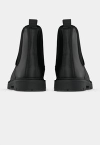 Botas de tobillo de cuero negro con una textura suave, que cuentan con paneles laterales elásticos y una suela de goma resistente diseñada para la durabilidad.