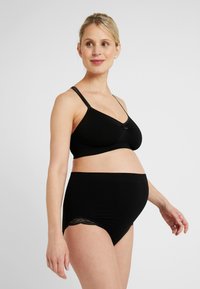 Zwarte zwangerschapsbh met verstelbare banden, gemaakt van zachte stof, en een strikdetail aan de voorkant; gecombineerd met hoge zwarte zwangerschapsunderwear met kantafwerking.