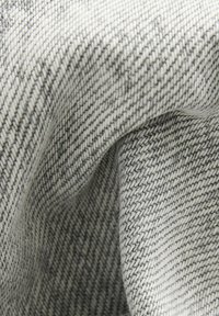 Tissu tissé gris avec un motif texturé, présentant un léger éclat et une surface douce, plié pour montrer son épaisseur et les détails de tissage.
