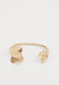 Pulsera de metal dorado con cintas que presenta dos acentos en forma de hoja en cada extremo, superficie lisa y diseño abierto para un ajuste ajustable.