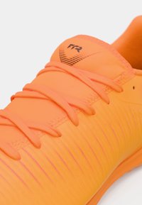 Leuchtend orangefarbener Sportschuh mit strukturiertem Obermaterial, schwarzer Markenkennzeichnung, dünnen Schnürsenkeln und einem stromlinienförmigen Design für verbesserte Leistung.