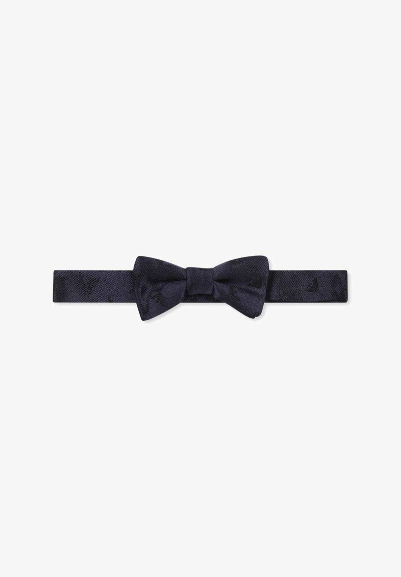 Papillon di seta blu navy con un motivo testurizzato. Presenta un nodo centrale e una tracolla regolabile per adattarsi a diverse misure.