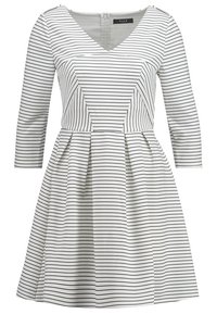 Pasiasta sukienka z dekoltem w kształcie litery V i rękawami o długości trzy czwarte. Wykonana z miękkiego materiału, posiada dopasowaną górę i rozkloszowany dół. Zamek błyskawiczny z tyłu.