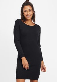 Abito in maglia nera con maniche lunghe, scollatura rotonda e polsini a costine. Il tessuto sembra morbido e liscio, con un discreto dettaglio del logo vicino all'orlo.