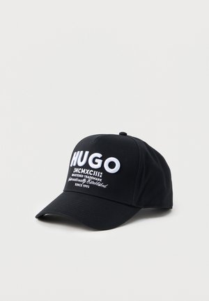 Schwarze Baseballmütze mit weiß gesticktem Text "HUGO" und "Seit 1993" auf der Vorderseite, dargestellt auf einem schlichten hellen Hintergrund.