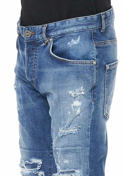 Jeans in denim blu sbiadito con una texture strappata, strappi visibili, un classico design a cinque tasche e chiusura con bottone metallico.