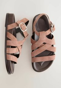 Sandali in suede marrone con più cinturini incrociati, fibbia regolabile e una suola liscia scura. Design distintivo incentrato sul comfort.