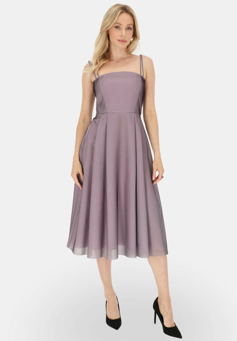 Liliowa sukienka bez rękawów z kwadratowym dekoltem, lejącą się spódnicą w kształcie litery A i przezroczystą fakturą. Połączona z czarnymi szpilkami.