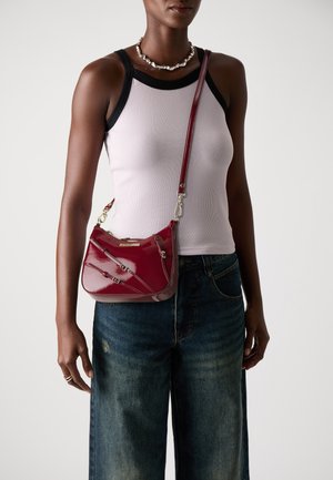 Red patent leather shoulder bag with a curved shape, featuring multiple angular zippers and a detachable shoulder strap.