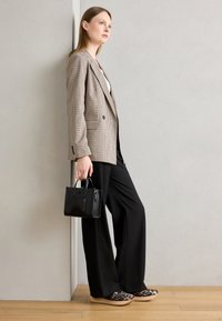 Blazer à carreaux marron, top blanc, pantalon large noir, chaussures en imprimé léopard et sac à main noir. Textures lisses et design structuré.