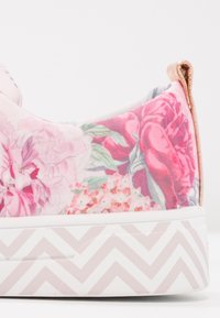 Baskets à imprimé floral avec un col matelassé, présentant des nuances de rose, vert et blanc, et une semelle blanche à motif chevron.