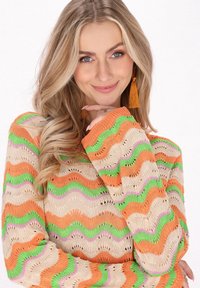 Gebreide trui met een golvende patroon in oranje, groen en roze op een beige basis. Lange mouwen met een losse pasvorm en open geweven textuur.