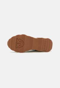 Potplat tenisica ima strukturiranu gumu svijetlosmeđe boje s logotipom, izbočinama i zakrivljenim petom. Ravna, čvrsta konstrukcija osigurava dobar grip i trajnost.