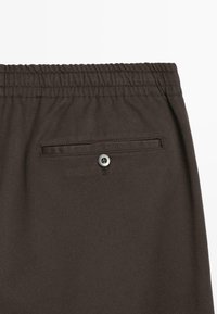 Brązowe, lekkie spodenki z elastycznym paskiem w talii, tylną kieszenią zapinaną na guzik oraz gładką fakturą.