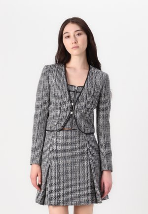 Tweed jacket and skirt set in black and white, featuring a cropped design, long sleeves, and contrasting trim with a textured finish.