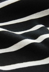 Tissu noir avec des rayures blanches horizontales, texturé avec un motif en relief. Les rayures sont espacées de manière égale, soulignant le contraste de couleur.