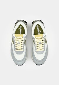 Gray and white sneakers with olive green accents, yellow laces, suede and mesh materials, round toe, and textured outsole. Logo on tongue.