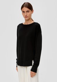 Schwarzer Strickpullover mit Rundhals, langen Ärmeln und geripptem Saum. Verfügt über eine lockere Passform und eine weiche Textur. Kombiniert mit hellen Hosen.
