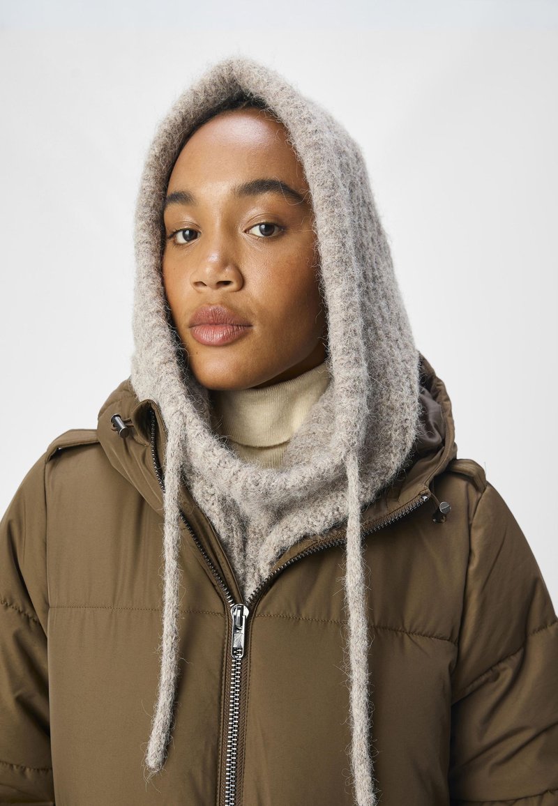 Brown padded jacket with a zip, featuring a light gray textured knitted scarf with drawstrings and a cream high-neck sweater underneath.