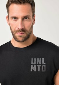 Zwart mouwloos T-shirt van katoen, met een grijze bedrukte logo "UNL MTD" aan de linkerkant, gladde textuur, ronde halslijn.
