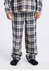 Plaid pajama set in blue, white, and brown. Soft flannel texture with button-up shirt and matching loose-fitting pants. Black socks visible.