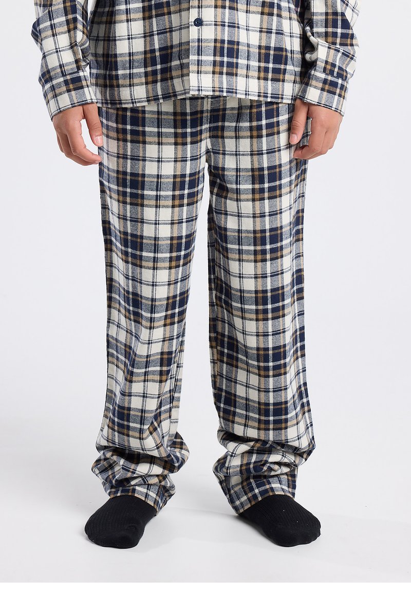 Plaid pajama set in blue, white, and brown. Soft flannel texture with button-up shirt and matching loose-fitting pants. Black socks visible.