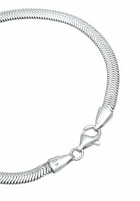 Sudraba toņa metāla kaklarota ar elastīgu zivs kaula rakstu, aprīkota ar drošu omāra aizdari un atzīmēta ar 925 zīmi, kas norāda uz sterlingsudrabu.