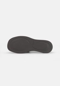 Black rubber shoe sole with a smooth texture, contoured design, and subtle branding. Rounded edges and a flat profile for even support.