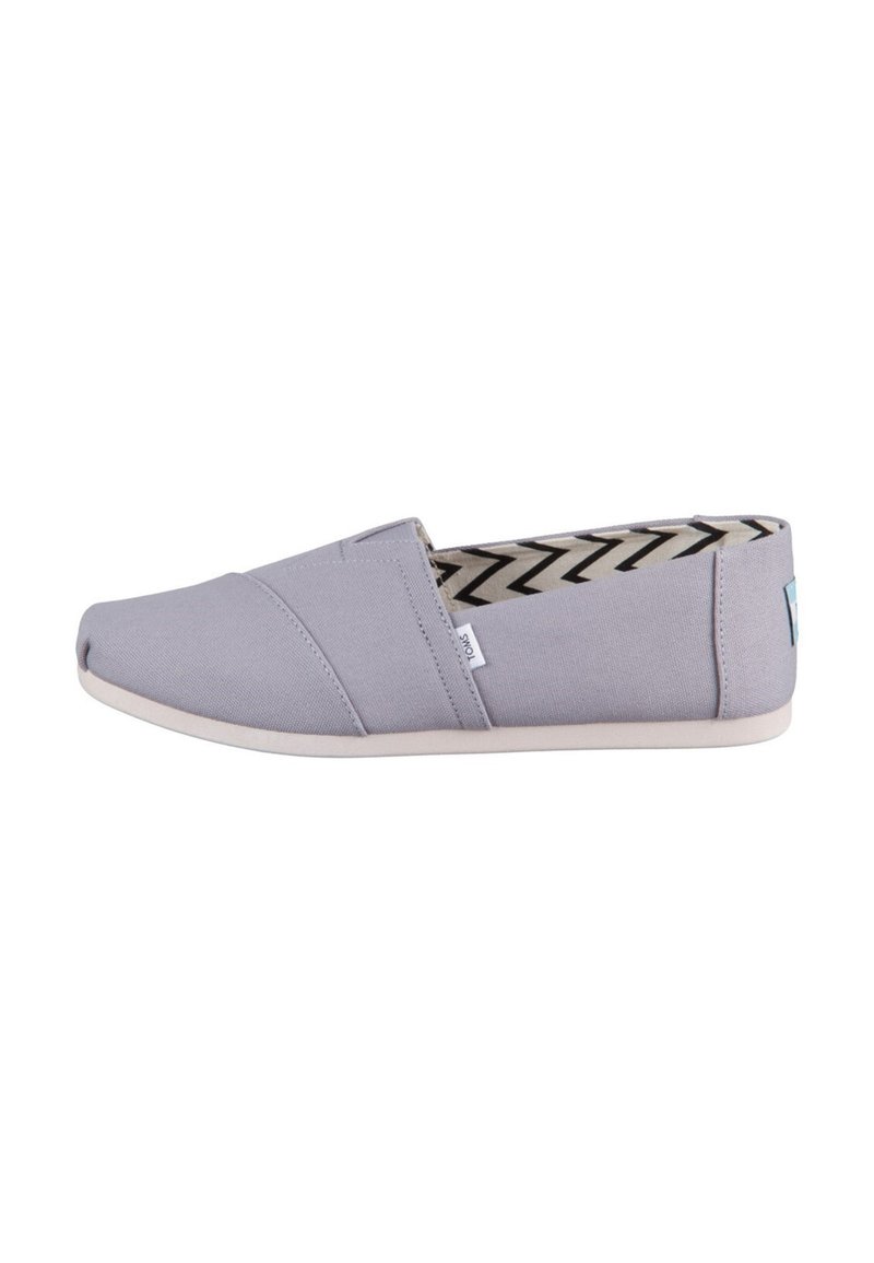 Scarpa slip-on in tela grigia con suola piatta, caratterizzata da cuciture diagonali e fodera a motivo chevron in bianco e nero.
