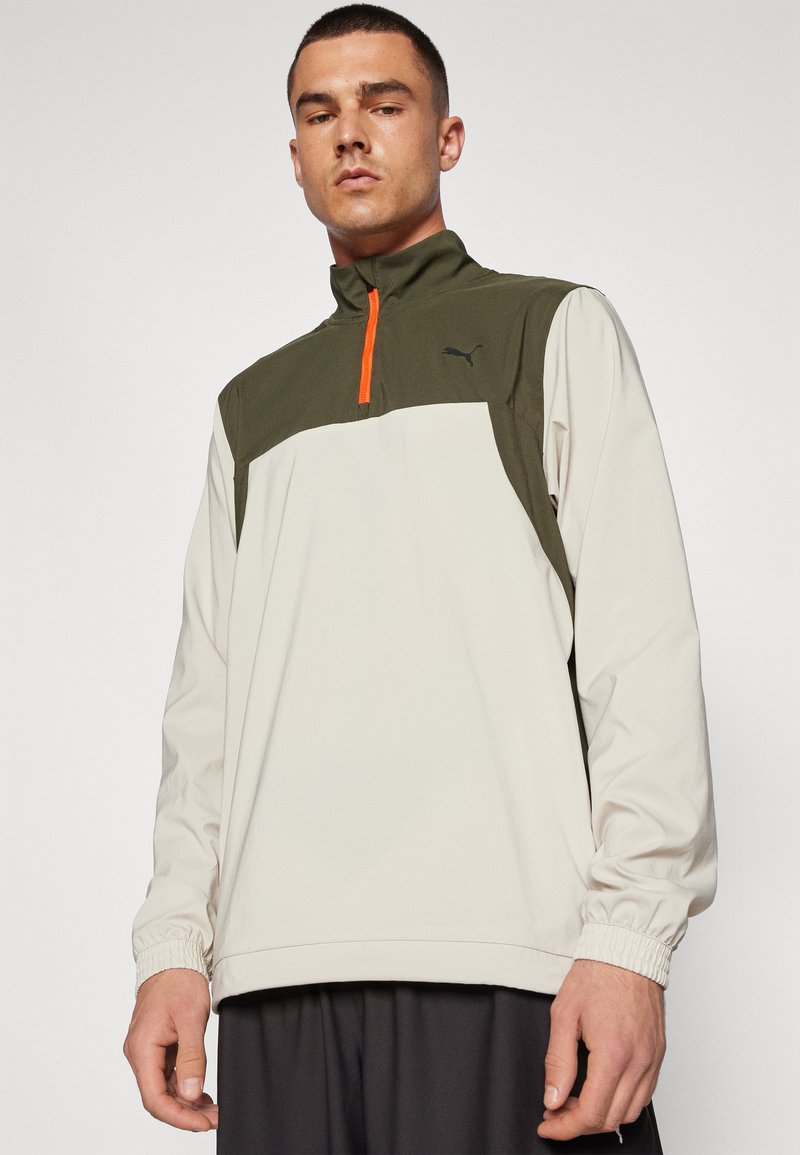 Lichte pullover in crème en olijfgroen, met een kwart-rits, elastische boorden en een contrasterende oranje ritsdetail.