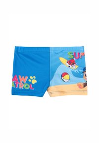 Pantaloni da bagno blu con la scritta "PAW PATROL", caratterizzati da personaggi dei cartoni animati in una scena da spiaggia con una tavola da surf e una palla. Realizzati in tessuto liscio.