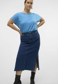 Modra majica s kratkimi rokavi, kombinirana s dolgo temno denim krilo z bočnim razporkom, oblečena s črnimi škornji do kolen.