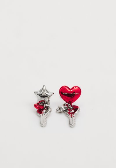 Porte-clés argenté avec des charms en forme d'étoile et de cœur rouge, portant la marque "Marc Jacobs" sur le cœur. Fini lisse et brillant.
