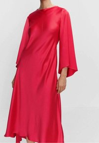 Robe en satin rouge avec de longues manches ballon, encolure ronde et ourlet asymétrique. Texture lisse avec une silhouette fluide.