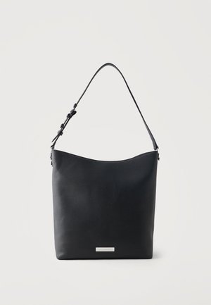 Sac bandoulière en cuir noir avec sangle réglable et plaque rectangulaire argentée du logo de la marque au centre devant.