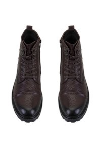 Bruine leren enkellaarsjes met een textuur, ronde neus, vetersluiting aan de voorkant en een zijrits. Voorzien van een rubberen zool voor grip.