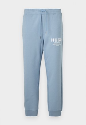 Light blue sweatpants made of soft fabric, featuring an elastic waistband with a drawstring and white logo print on the left thigh.