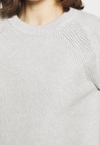 Hellgrauer gestrickter Pullover mit rundem Halsausschnitt, strukturiertem Muster an den Schultern und einem weichen, dickeren Stoff.