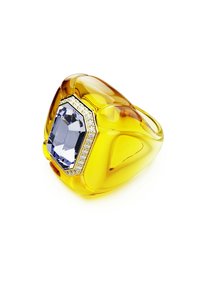 Anillo de declaración amarillo que presenta una gran gema de luz azul en forma octogonal, rodeada de pequeños diamantes brillantes, sobre un fondo blanco.