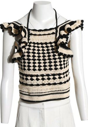 Haut sans manches noir et beige en crochet avec bretelles à volants et motif géométrique sur un buste de mannequin blanc.