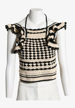Haut sans manches noir et beige en crochet avec bretelles à volants et motif géométrique sur un buste de mannequin blanc.