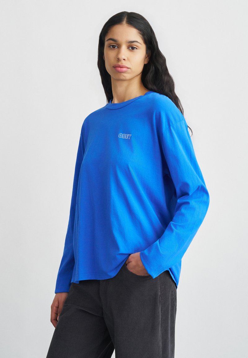 Μπλε μακρυμάνικη μπλούζα από απαλό βαμβάκι με στρογγυλή λαιμόκοψη, με μικρό κεντημένο λογότυπο "OBEY" στο στήθος.