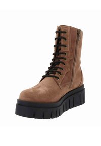 Bottine en daim marron avec lacets noirs, fermeture éclair sur le côté, semelle épaisse noire et finition texturée. Design distinctif avec bout renforcé.