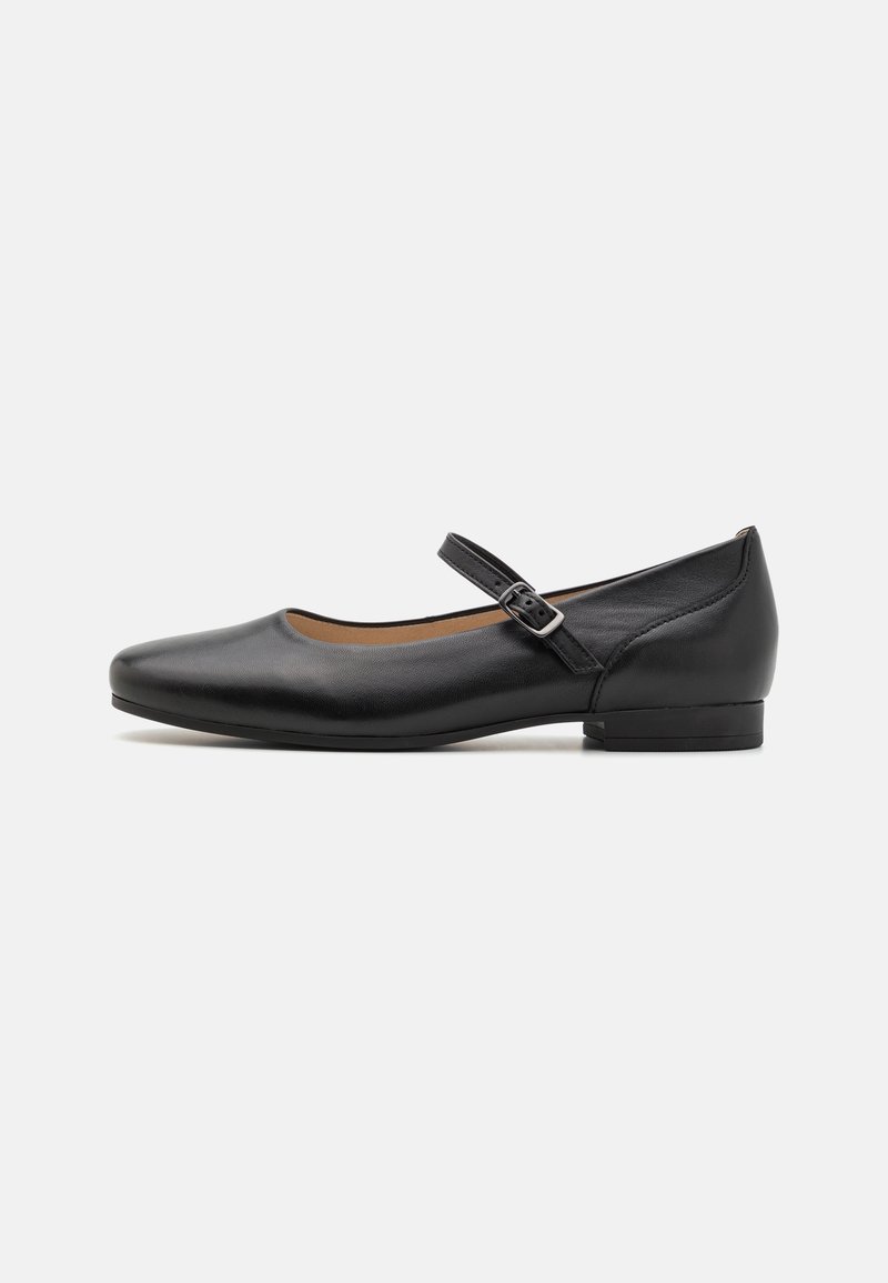 Chaussure plate Mary Jane en cuir noir avec un bout arrondi, une bride réglable à boucle et un petit talon sur un fond blanc uni.